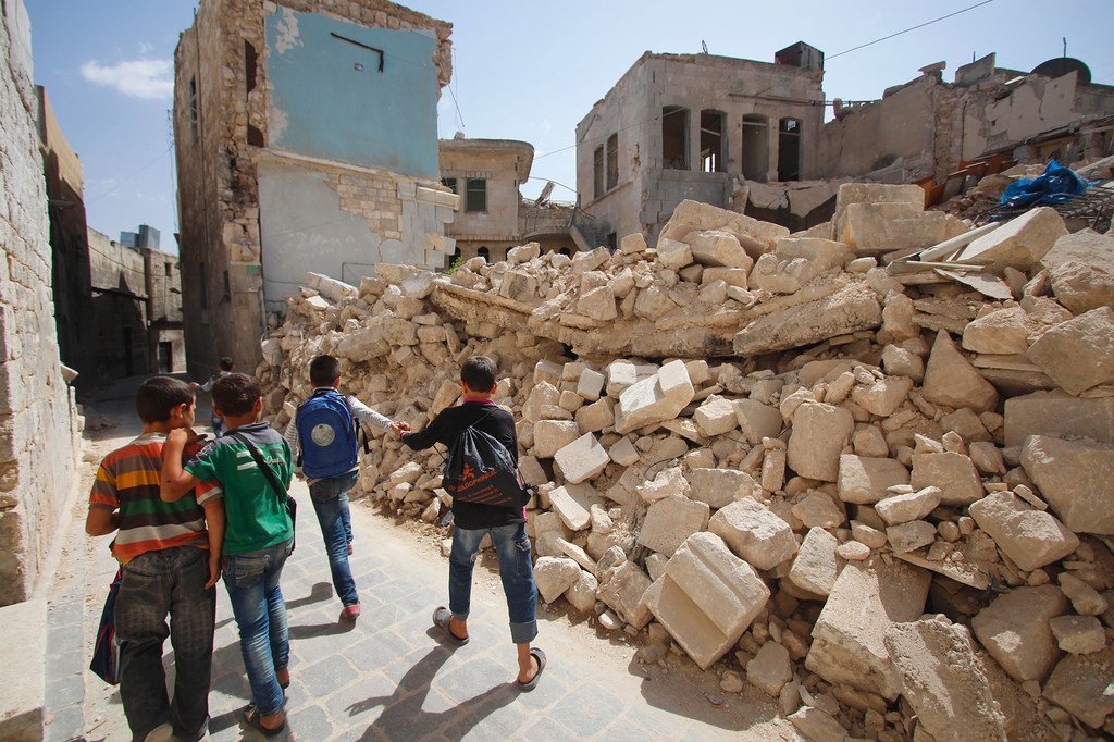 叙利亚阿勒颇东部，放学回家的儿童走过一片废墟。