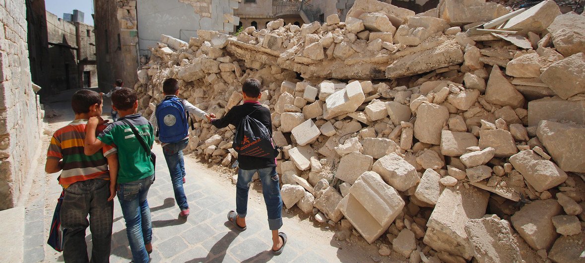 طلاب مدارس في شرقي حلب في الجمهورية العربية السورية يعودون من أول يوم دراسي ويسيرون بين منازل مدمرة على جنبات الطريق. (21 أيلول/سبتمبر 2016)