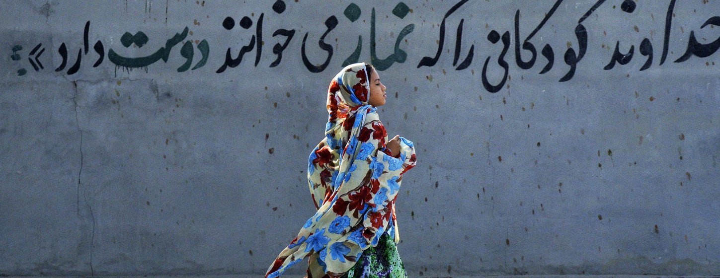 Une jeune fille portant le hijab en Iran passe en courant devant une peinture murale indiquant, en persan, "Dieu aime les enfants qui disent leur 'namaz' [prières]". ( Archive)