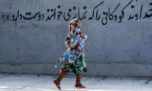 A girl wearing her hijab in Iran runs past a mural stating, in Persian, “God loves children who say their ‘namaz’ [prayers].” (File)