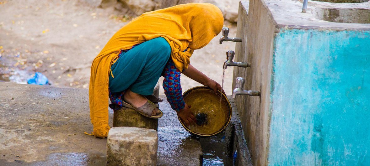 Женщина в Пакистане наполняет канистру питьевой водой из колонки