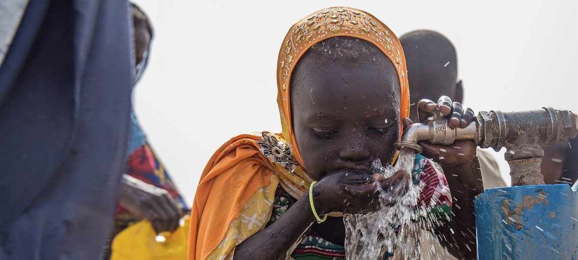 Menina bebe água em campo para pessoas deslocadas pela violência