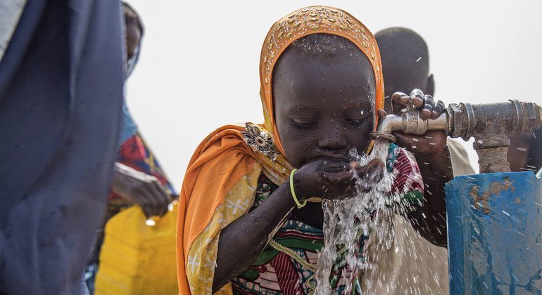 Menina bebe água em campo para pessoas deslocadas pela violência