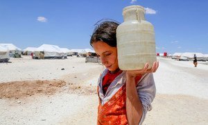 فتاة تحمل المياه في مخيم مؤقت في عين عيسى بسوريا.