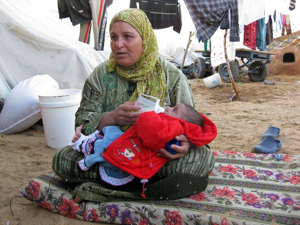 一名流离失所的妇女在加沙喂养一名儿童。(档案照片)