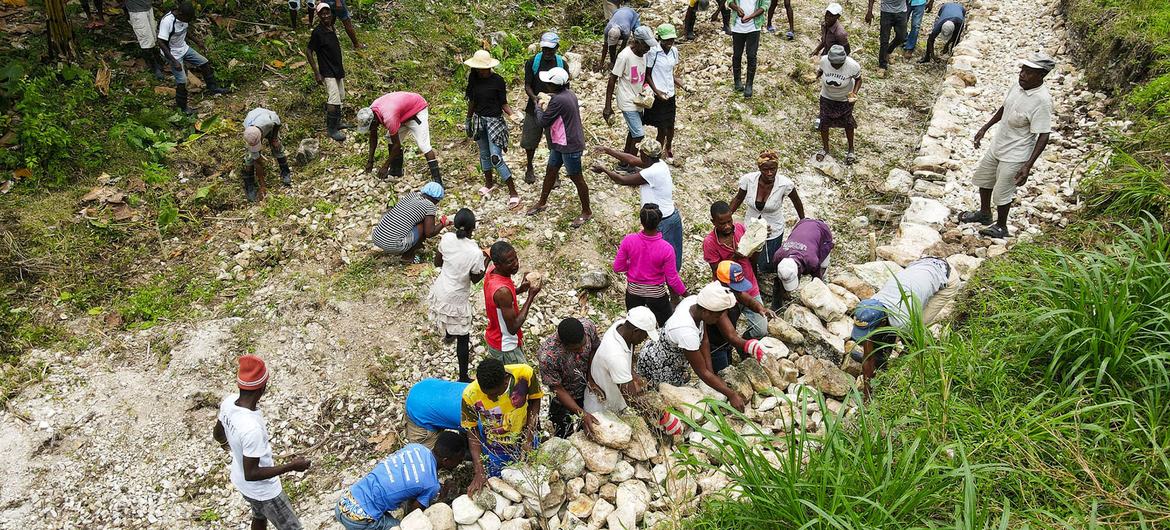 يعمل أفراد مجتمع محلي في جنوب غرب هايتي معًا لإصلاح طريق تضرر من الزلزال.