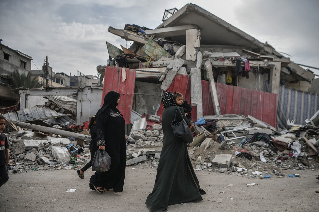 Des femmes marchent dans les rues détruites de Gaza.