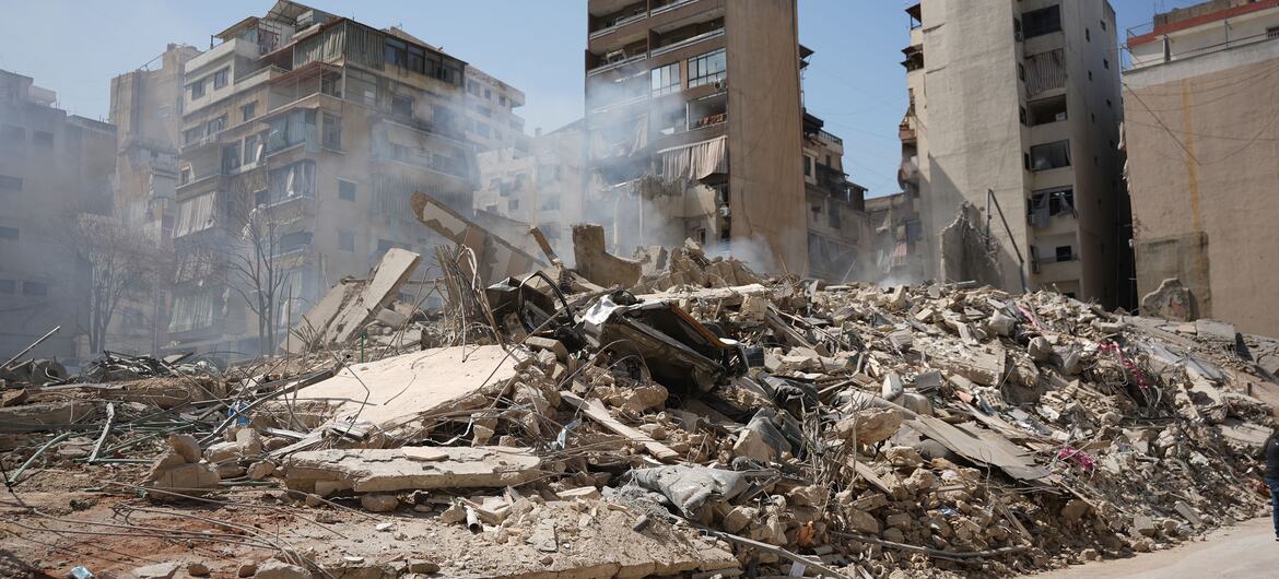 A street in the Bashura neighborhood of Beirut, Lebanon, covered in rubble and debris from destroyed buildings following airstrikes, with smoke rising from the wreckage.