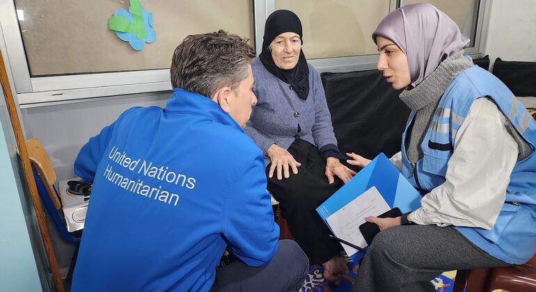 يجلس توم فلتشر، منسق الإغاثة الطارئة التابع للأمم المتحدة، وهو يرتدي سترة الإنسانية الزرقاء التابعة للأمم المتحدة، ويتحدث مع ستة أيوب، وهي امرأة مسنة في حجاب أسود نزحت بسبب النزاع. وهم في مدرسة عمر أونسي العامة، ملجأ جماعي في بيروت، يرافقها امرأة أخرى في حجاب وجليد أزرق تحمل مجلد.