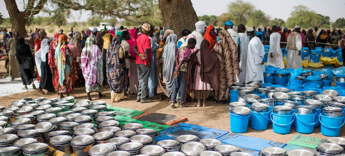 逃离苏丹暴力、抵达乍得的人们正在领取联合国提供的食品和其他救济物品。