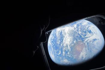 Silhouette d'un astronaute regardant la Terre à travers la fenêtre d'un vaisseau spatial.