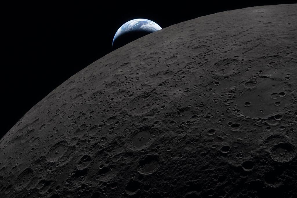 La Tierra se eleva sobre el horizonte craterizado de la Luna.