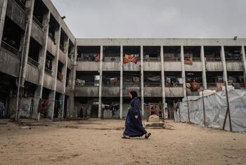 Una mujer embarazada camina por el patio de un edificio escolar dañado en Jabalia, Gaza, que sirve como lugar de desplazamiento, con tiendas de campaña de UNICEF cerca.