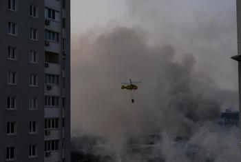 A state emergency service helicopter carries water as it flies over residential Kyiv neighbourhoods blanketed in smoke. 