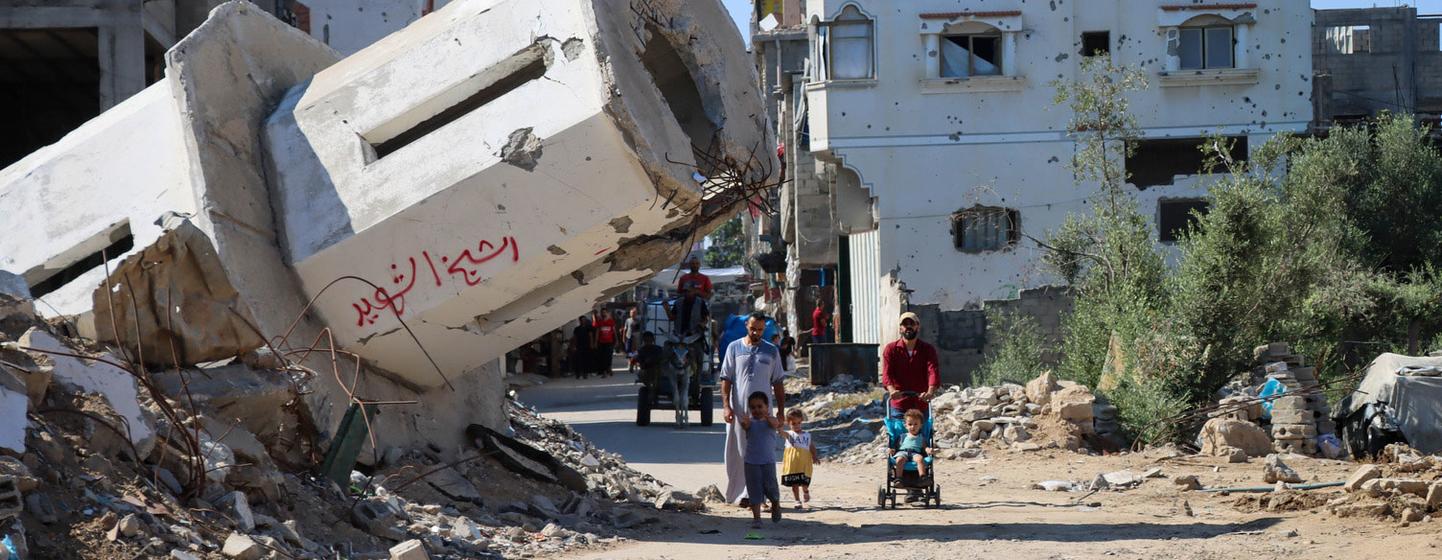 Una familia pasa frente a una mezquita destruida en Gaza.