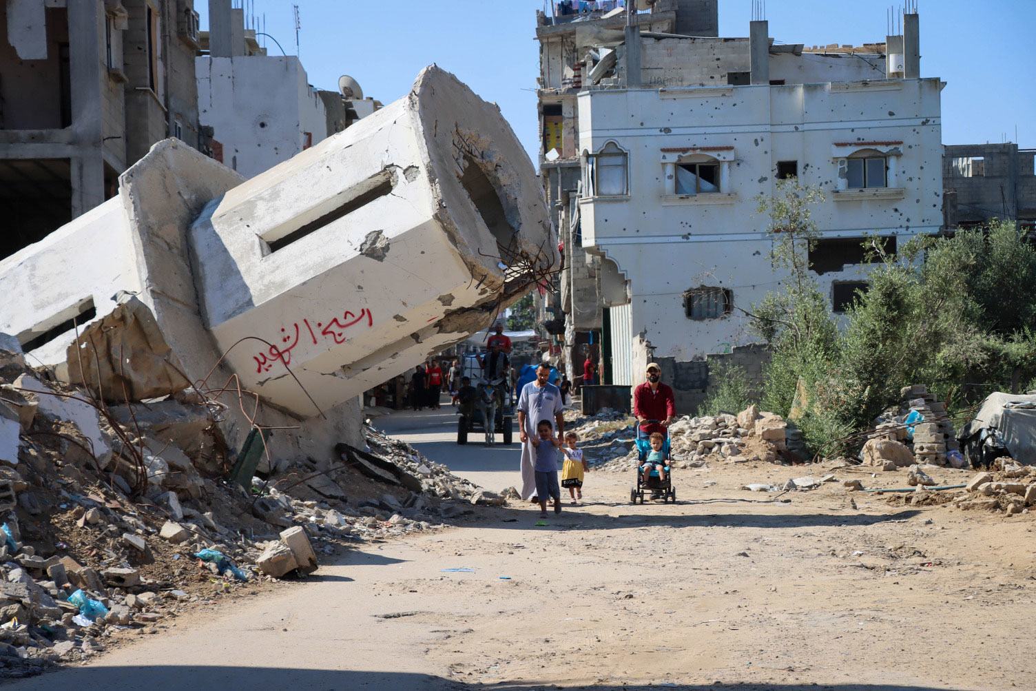 Una familia pasa frente a una mezquita destruida en Gaza.