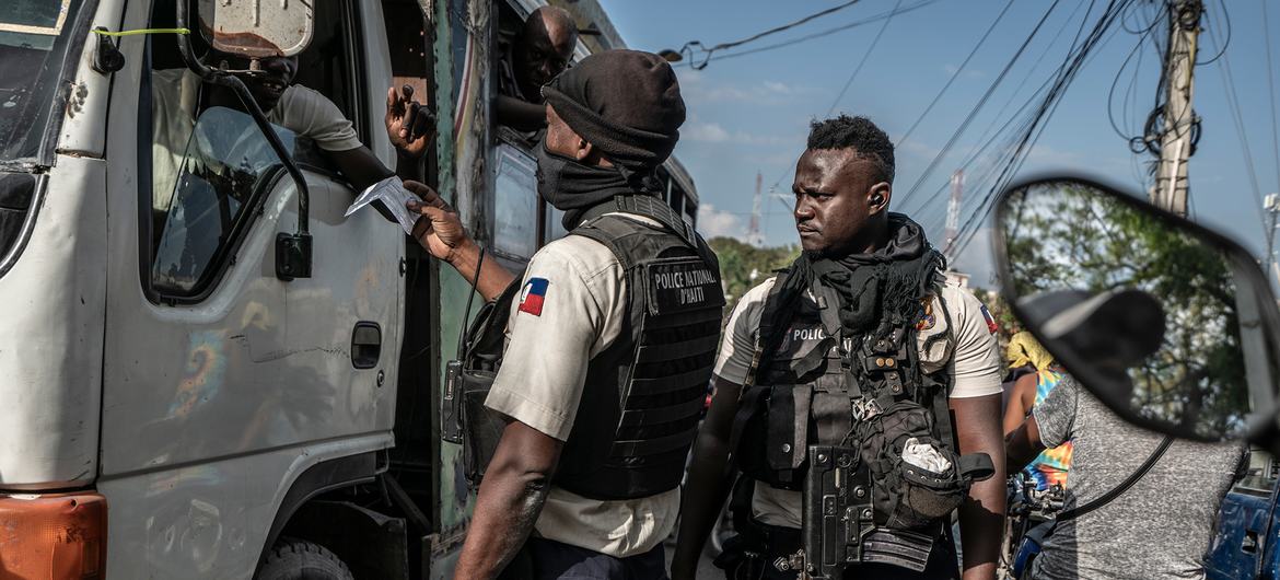 Haitian police check a driver's papers at a checkpoint.