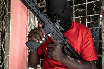 An armed man in a black mask and red shirt holds an assault rifle in the Delmas 3 area of Port-au-Prince, Haiti.