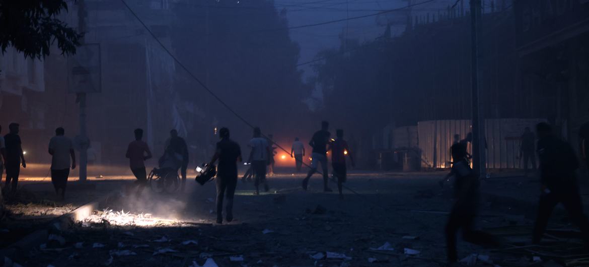 Personas caminan entre los escombros a oscuras en Rafah debido a un corte de electricidad.