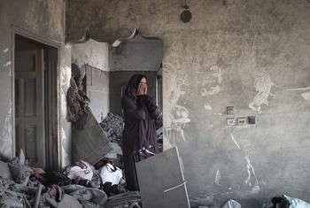 ग़ाज़ा पट्टी के एक दक्षिणी इलाक़े में, एक महिला, इसराइली बमबारी में तबाह हुए अपने घर को देखते हुए.
