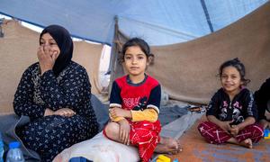 Members of a family rest in a tent after fleeing their home in Lebanon.