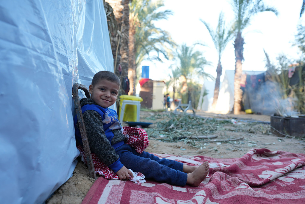 A boy sits outside the tent he now calls home in the south of the Gaza Strip.