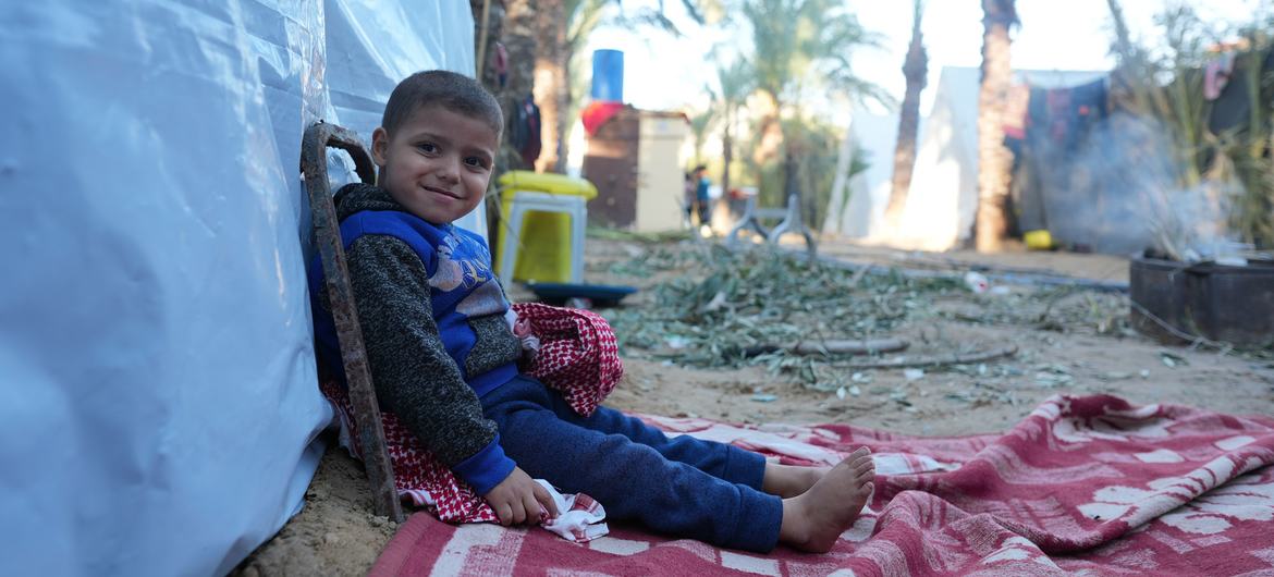 Un petit garçon est assis devant la tente qu’il habite désormais dans le sud de la bande de Gaza.