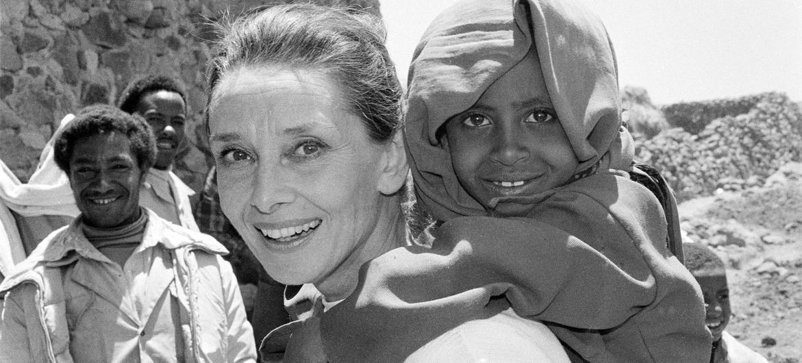 UNICEF Goodwill Ambassador Audrey Hepburn smiles as she carries a child on her back in the northern town of Mehal Meda in Shoa province, Ethiopia.