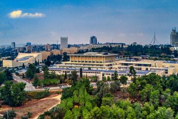 Vista aérea del edificio de la Knesset en Jerusalén, Israel, rodeada de verde y horizonte urbano.