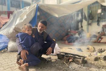 Un hombre y un niño sentados junto a una pequeña hoguera en Nuseirat, en el centro de Gaza.