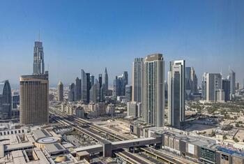 Aerial view of Dubai's modern skyline featuring numerous skyscrapers and elevated highways under a clear blue sky.