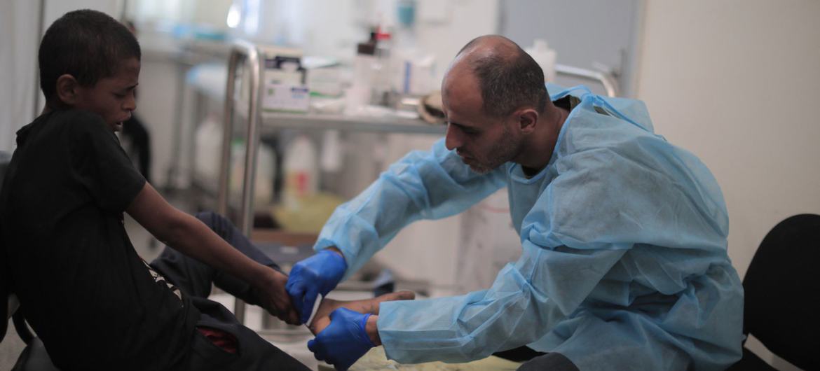 一名近东救济工程处工作人员在加沙为一名男孩提供医疗服务。