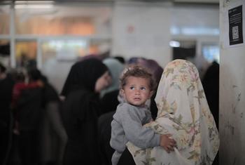 Une femme amène un enfant pour une consultation de santé à Gaza.