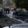 Спасатели проходят по улице в Днепре, усеянной сгоревшими автомобилями и обломками.