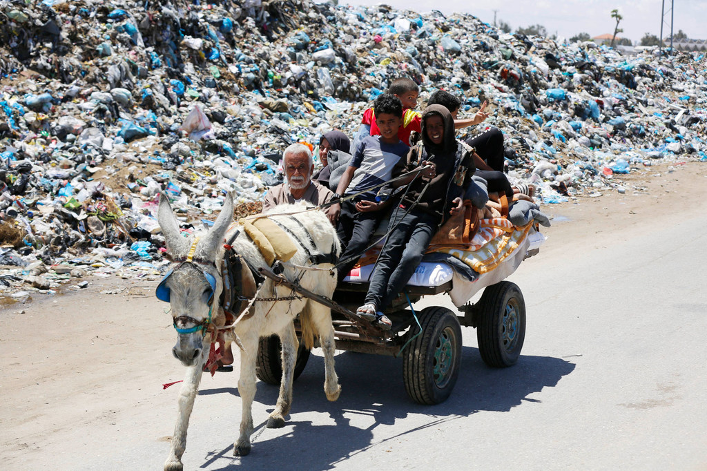 Une famille à Gaza passe le long d’une route bordée d’ordures.