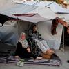 Two women sit outside their temporary shelter in Gaza.