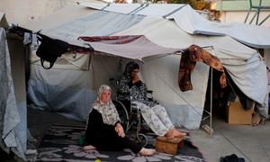 Two women sit outside their temporary shelter in Gaza.