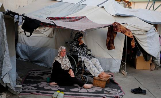 Two women sit outside their temporary shelter in Gaza.