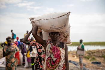 Wanawake wakishusha chakula katika bandari nchini Sudan Kusini ambako WFP husafirisha chakula kupitia mtumbwi ili kuepuka matone ya gharama ya juu.