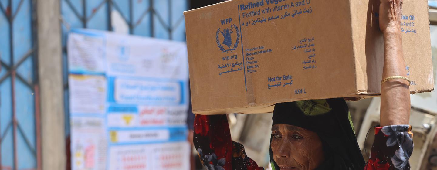 Une femme porte une boîte de rations alimentaires à Jabal Habashi à Taiz, au Yémen.