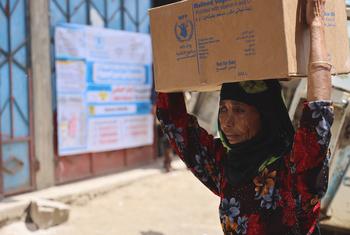 Une femme porte une boîte de rations alimentaires à Jabal Habashi à Taiz, au Yémen.