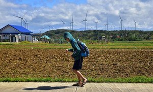 Un estudiante pasa frente a una granja de energía eólica en Filipinas.