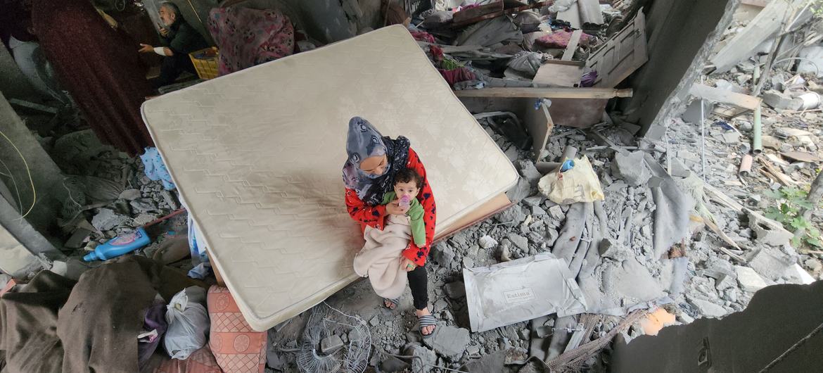 Una madre con su hijo recién nacido sobre los escombros de su casa bombardeada en Khan Younis. 