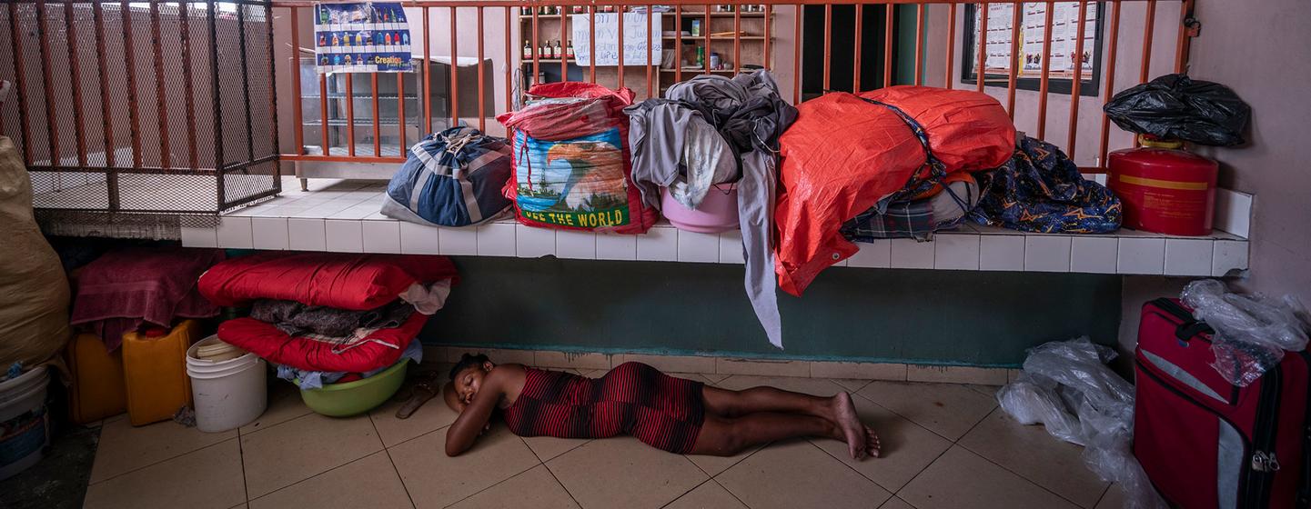 Une femme dort à même le sol d'un refuge à Port-au-Prince, en Haïti, entourée de ses affaires et d'autres personnes déplacées.