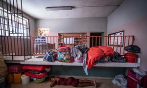 Une femme dort à même le sol d'un refuge à Port-au-Prince, en Haïti, entourée de ses affaires et d'autres personnes déplacées.