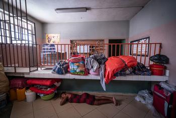 A woman sleeps on the floor of a shelter in Port-au-Prince, Haiti, surrounded by her belongings and other displaced individuals.