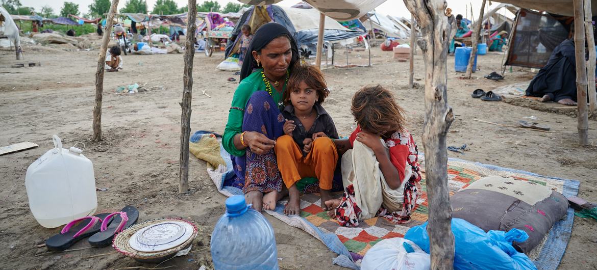 A family sits under a makeshift roof in Sindh province, Pakistan, after their home was damaged in a devastating flood.