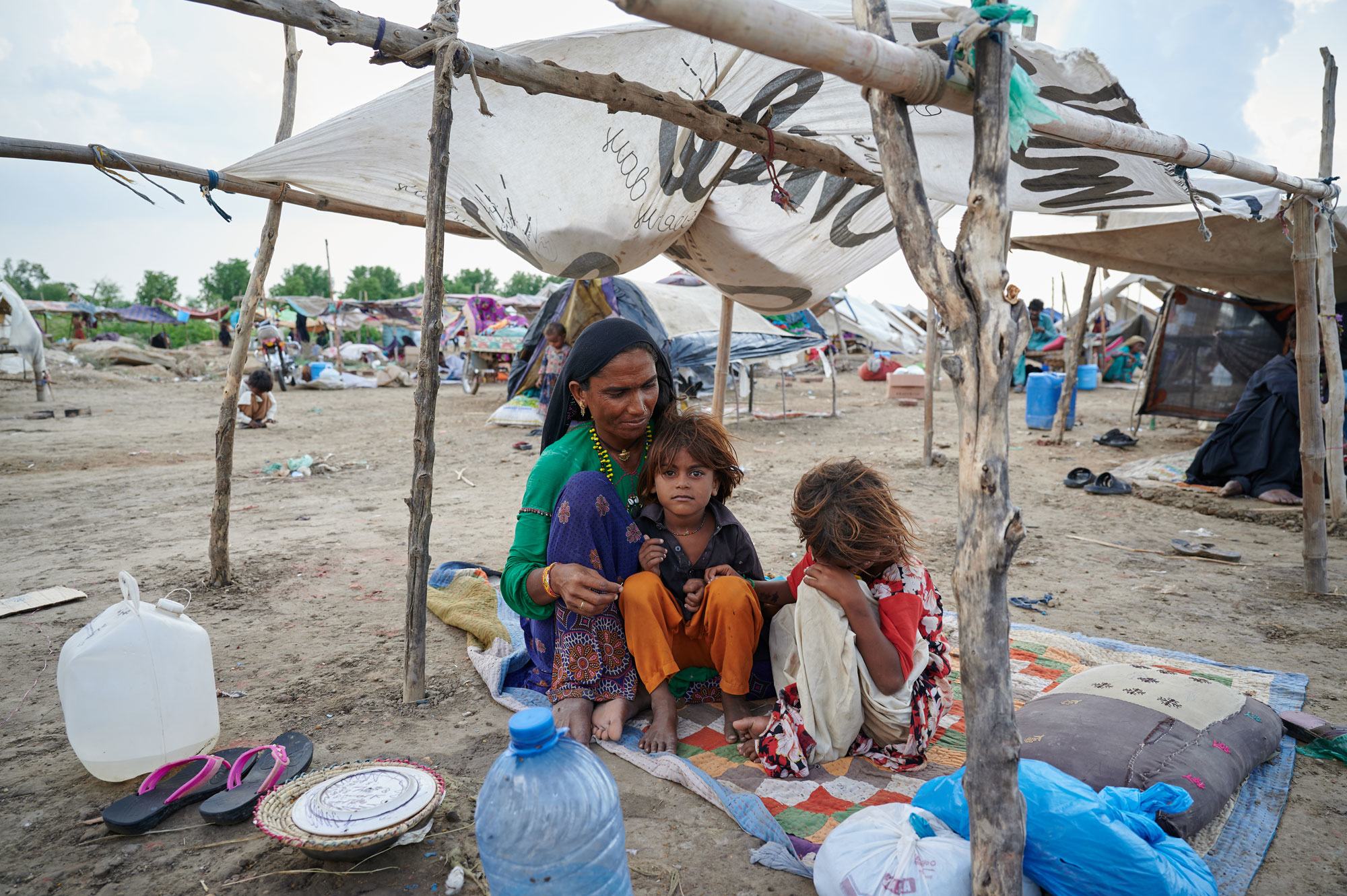 一个家庭坐在巴基斯坦信德省的一个临时避难场所，他们的家在毁灭性的洪水中遭到破坏。