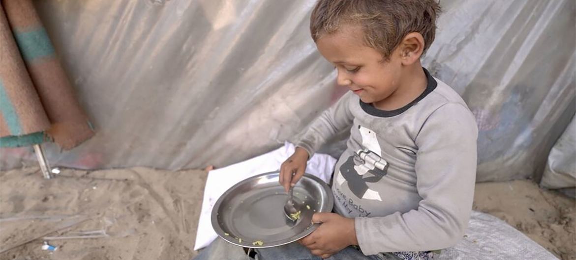 A small boy scoops up the last rice grains in his bowl. Hunger is soaring in Gaza and the WFP food allowed to enter is limited.