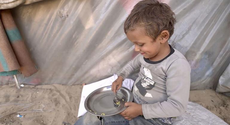 A little boy picks up the last grain of rice in his bowl and eats it. Hunger is growing in Gaza and WFP has received limited access to food.